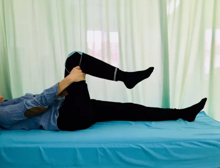 在床上弯曲和伸展膝关节:保持脚在床上滑动,尽可能弯曲膝关节